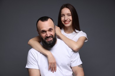 Portrait of happy daughter and father on dark grey background