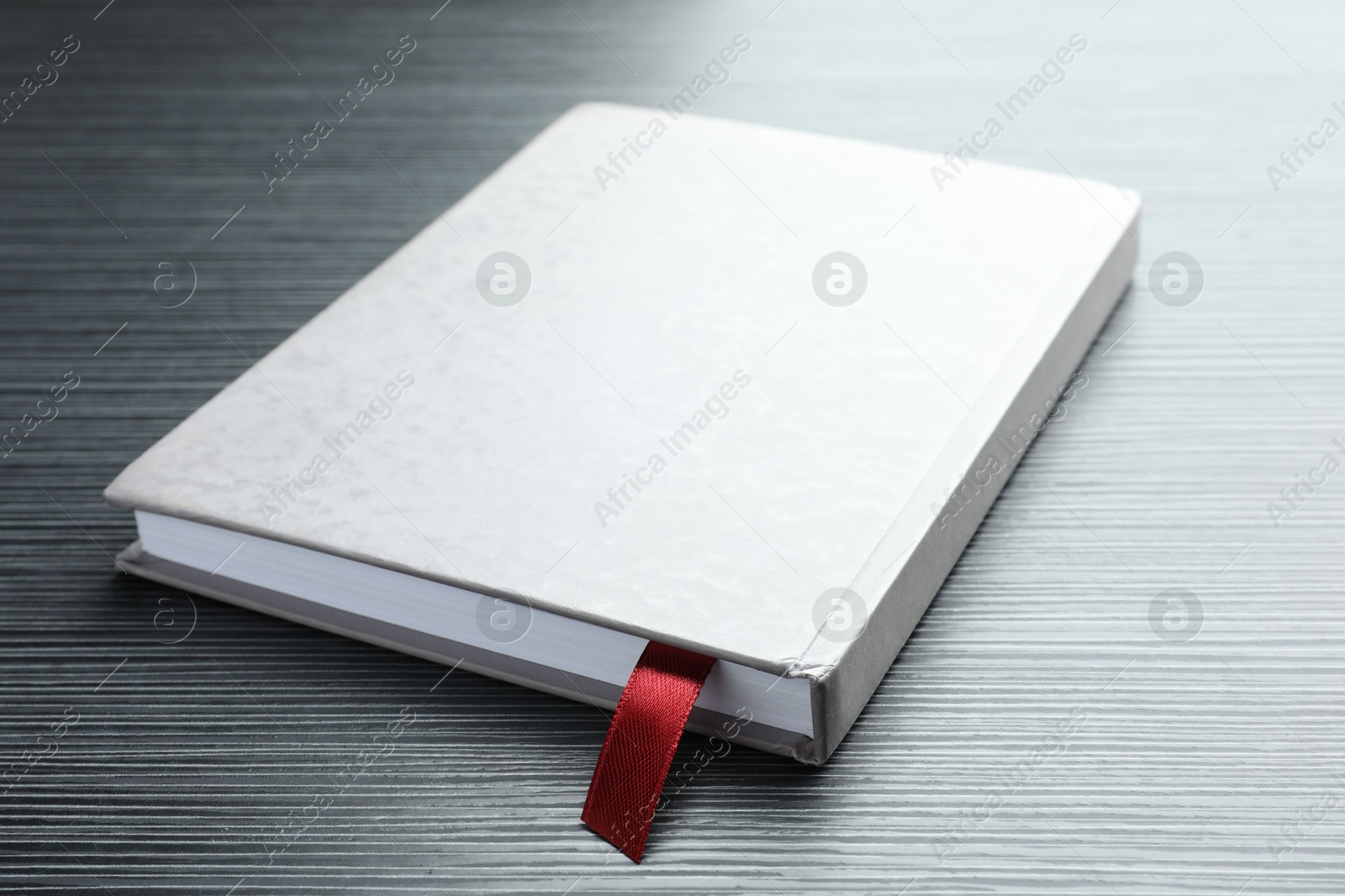 Book with red ribbon bookmark on black wooden table, closeup Photo of Book with red ribbon bookmark on black wooden table, closeup