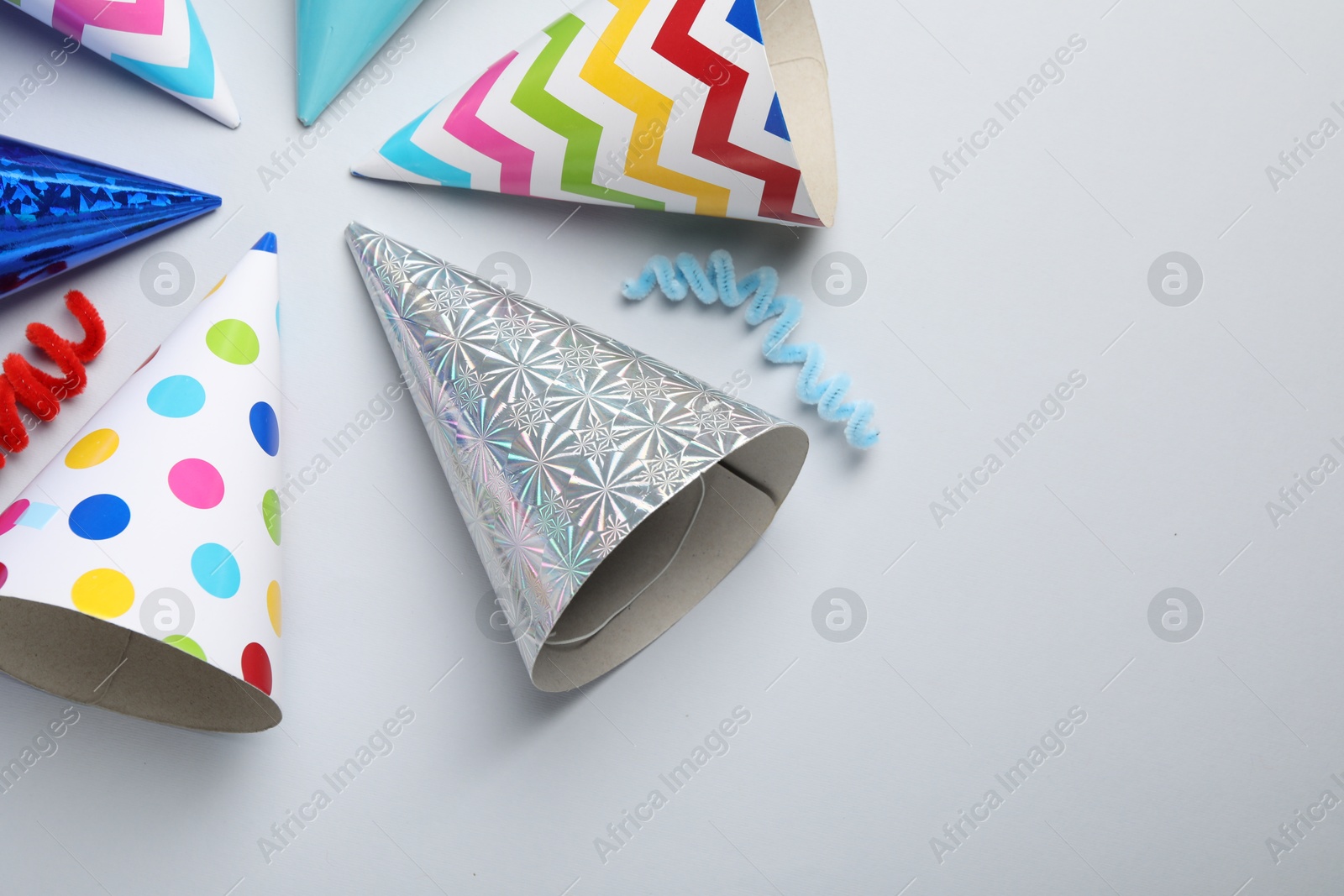 Colorful party hats on light grey background, flat lay. Space for text Photo of Colorful party hats on light grey background, flat lay. Space for text