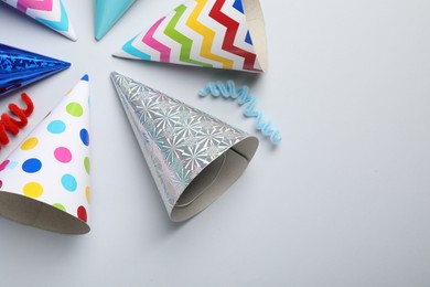 Photo of Colorful party hats on light grey background, flat lay. Space for text