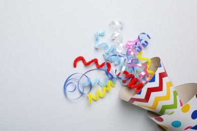 Photo of Colorful party hats and streamers on light grey background, flat lay. Space for text