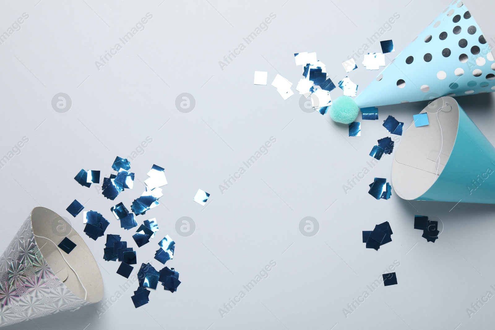 Colorful party hats and confetti on light grey background, flat lay. Space for text Photo of Colorful party hats and confetti on light grey background, flat lay. Space for text