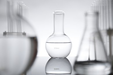 Laboratory glassware with liquid on mirror surface against light background