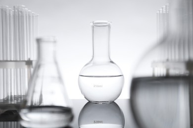 Photo of Laboratory glassware with liquid on mirror surface against light background