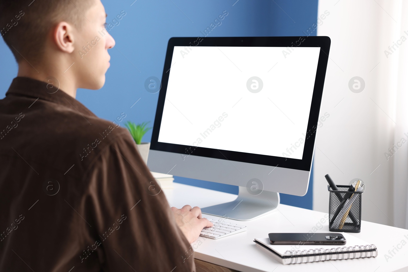 Photo of Man working on computer at white desk in office. Mockup for design