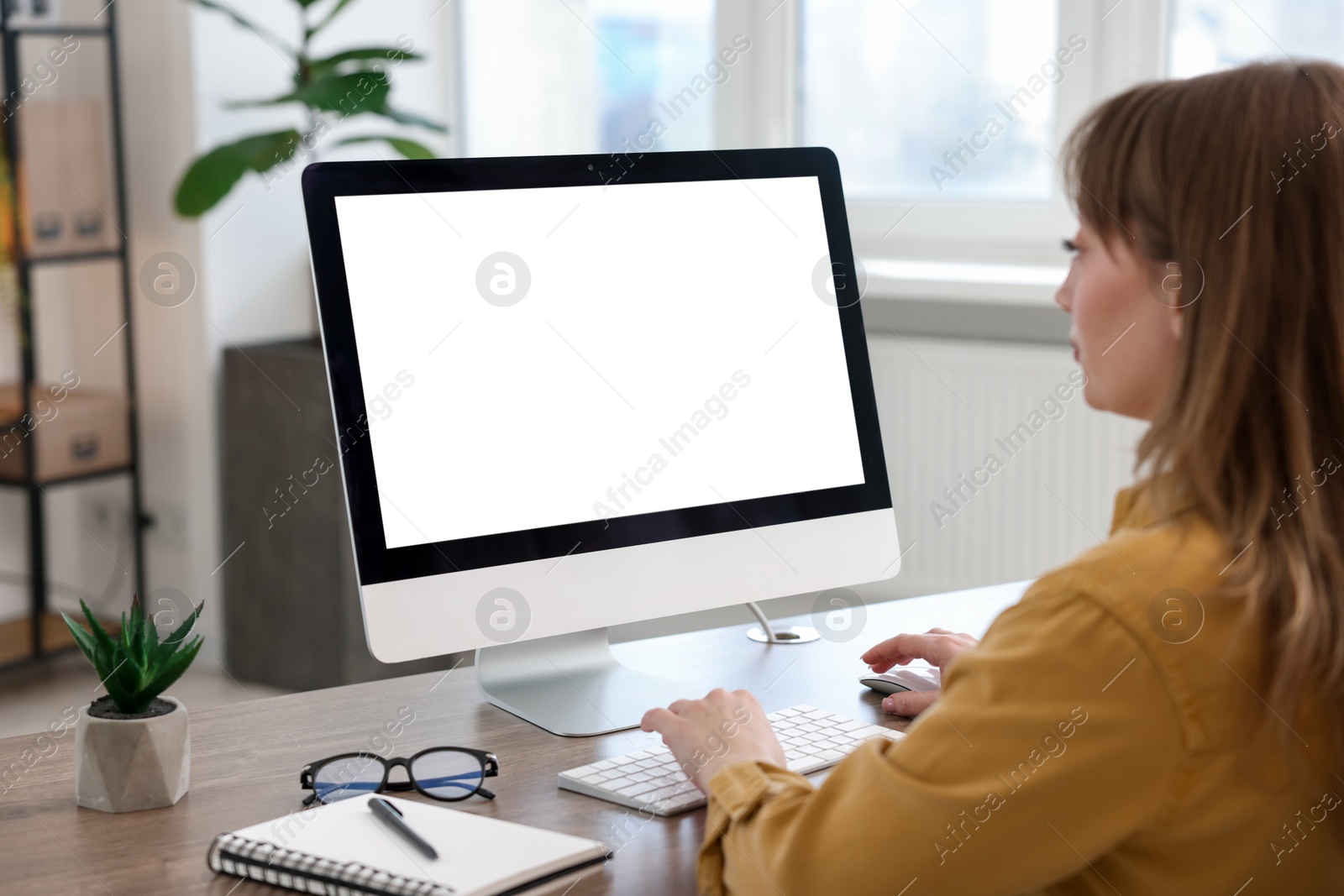 Photo of Woman working on computer at wooden desk in office. Mockup for design