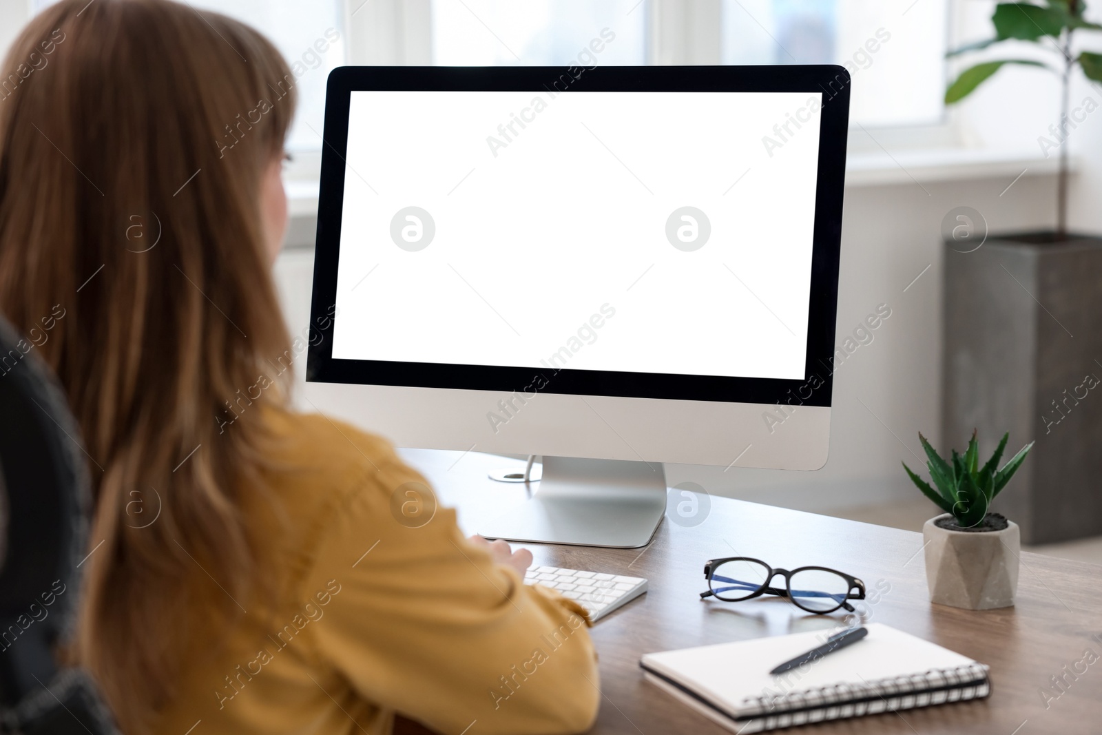 Photo of Woman working on computer at wooden desk in office. Mockup for design