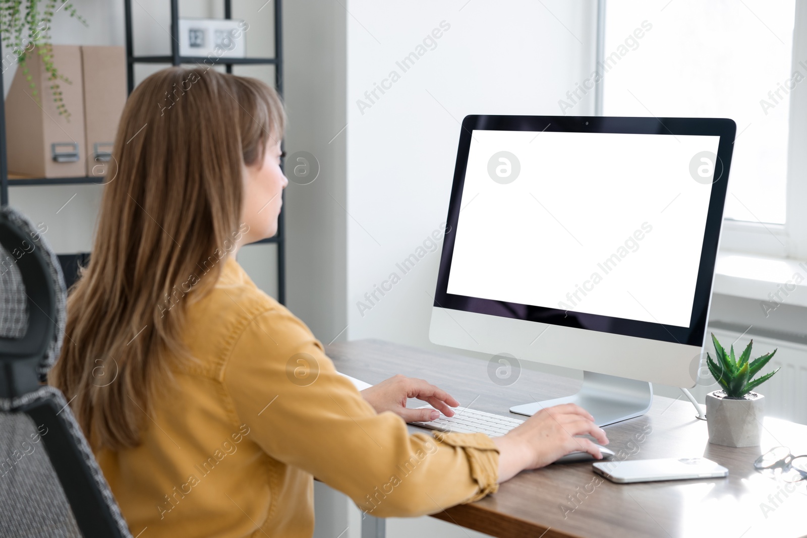 Photo of Woman working on computer at wooden desk in office. Mockup for design