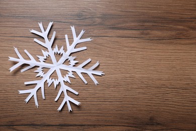 Photo of One paper snowflake on wooden background, top view. Space for text