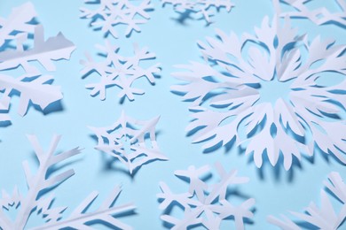 Photo of Beautiful paper snowflakes on light blue background, closeup