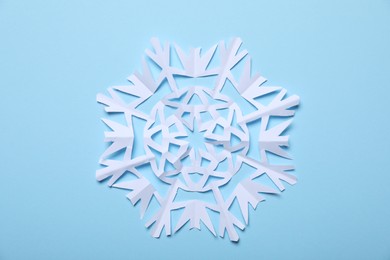 Photo of One paper snowflake on light blue background, top view