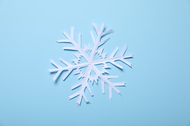 Photo of One paper snowflake on light blue background, top view