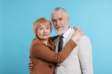 Lovely senior couple hugging on light blue background