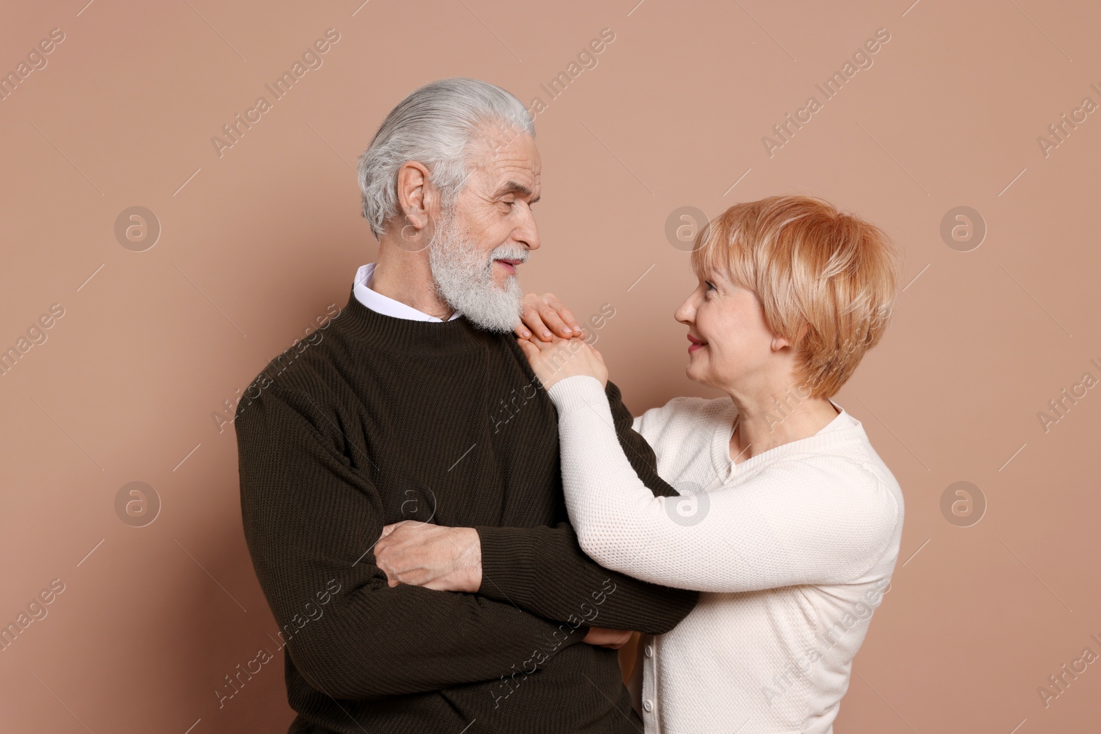 Photo of Lovely senior couple looking at each other on beige background