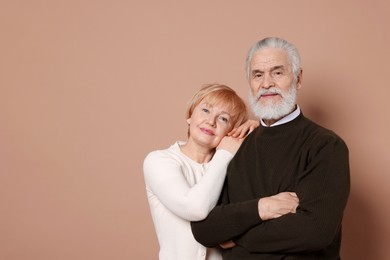 Portrait of lovely senior couple on beige background. Space for text