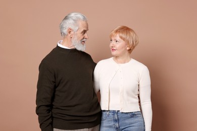 Photo of Lovely senior couple looking at each other on beige background