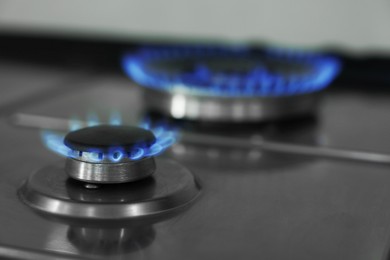 Photo of Gas burners with blue flame on stove, closeup