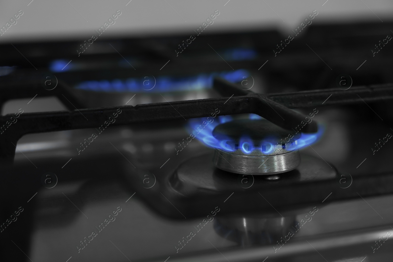 Photo of Gas burners with blue flame on stove, closeup