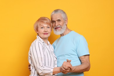 Photo of Portrait of lovely senior couple holding hands on orange background