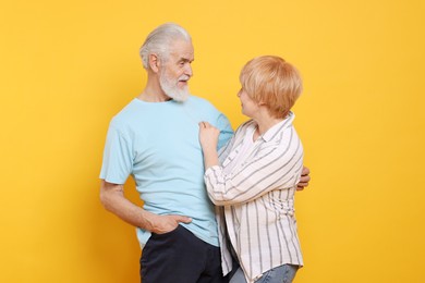 Photo of Lovely senior couple looking at each other on orange background