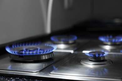 Photo of Gas burners with blue flame on stove, closeup