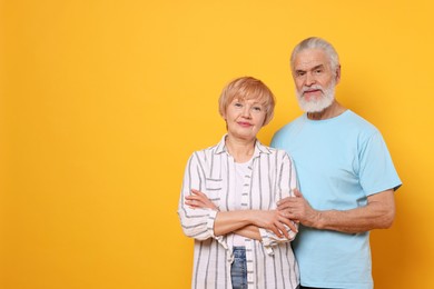 Portrait of lovely senior couple on orange background. Space for text