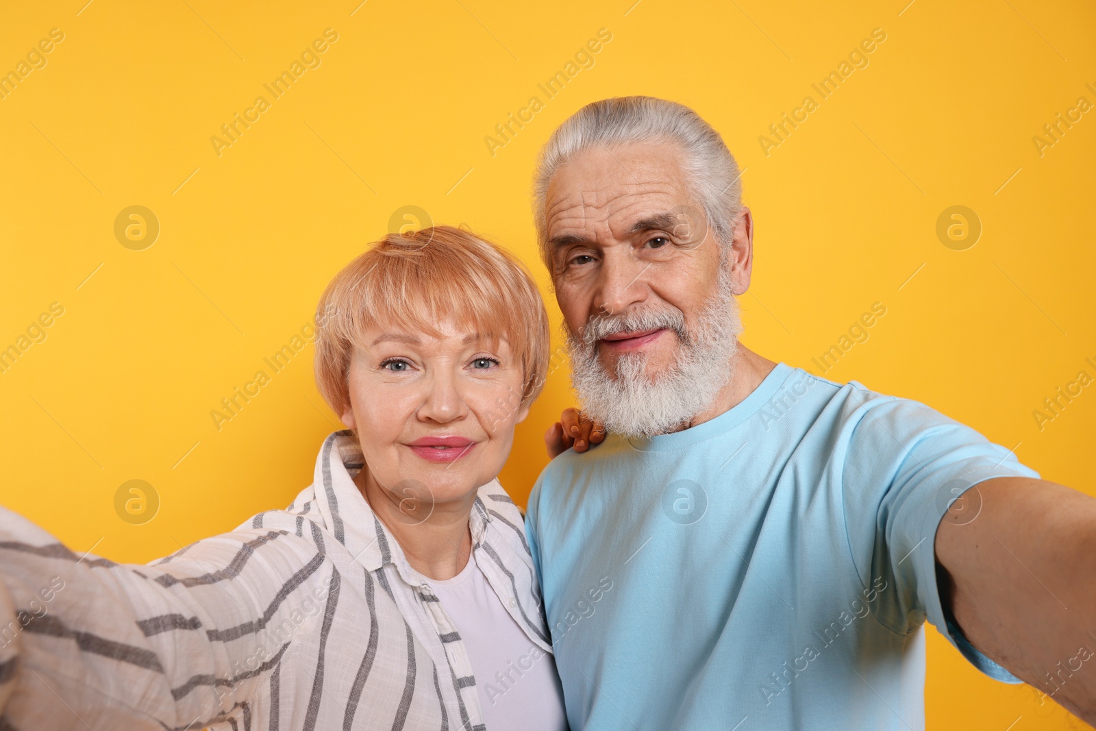 Photo of Lovely senior couple taking selfie on orange background