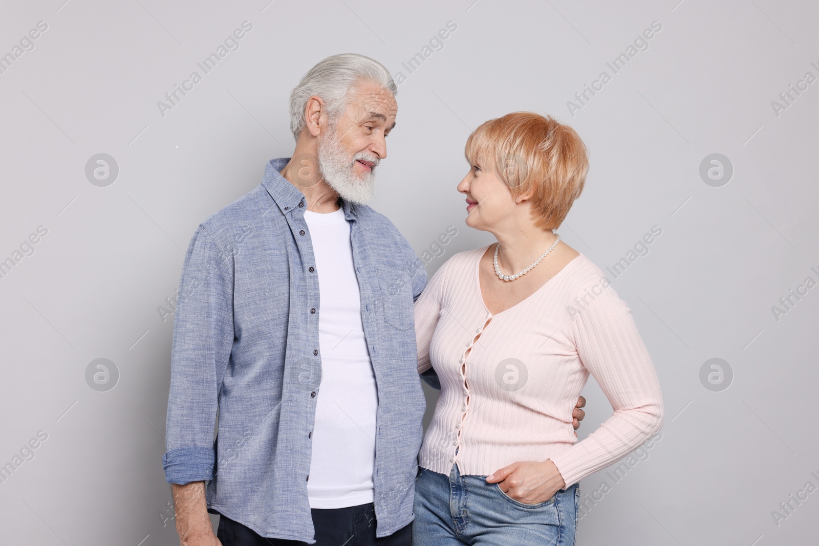 Photo of Lovely senior couple looking at each other on grey background