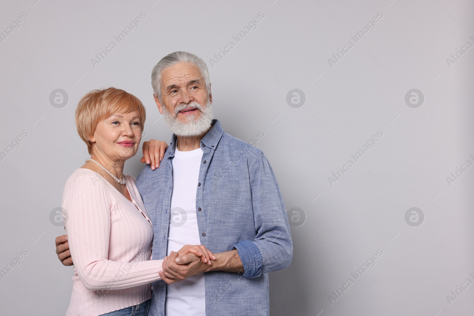 Photo of Lovely senior couple holding hands on grey background. Space for text