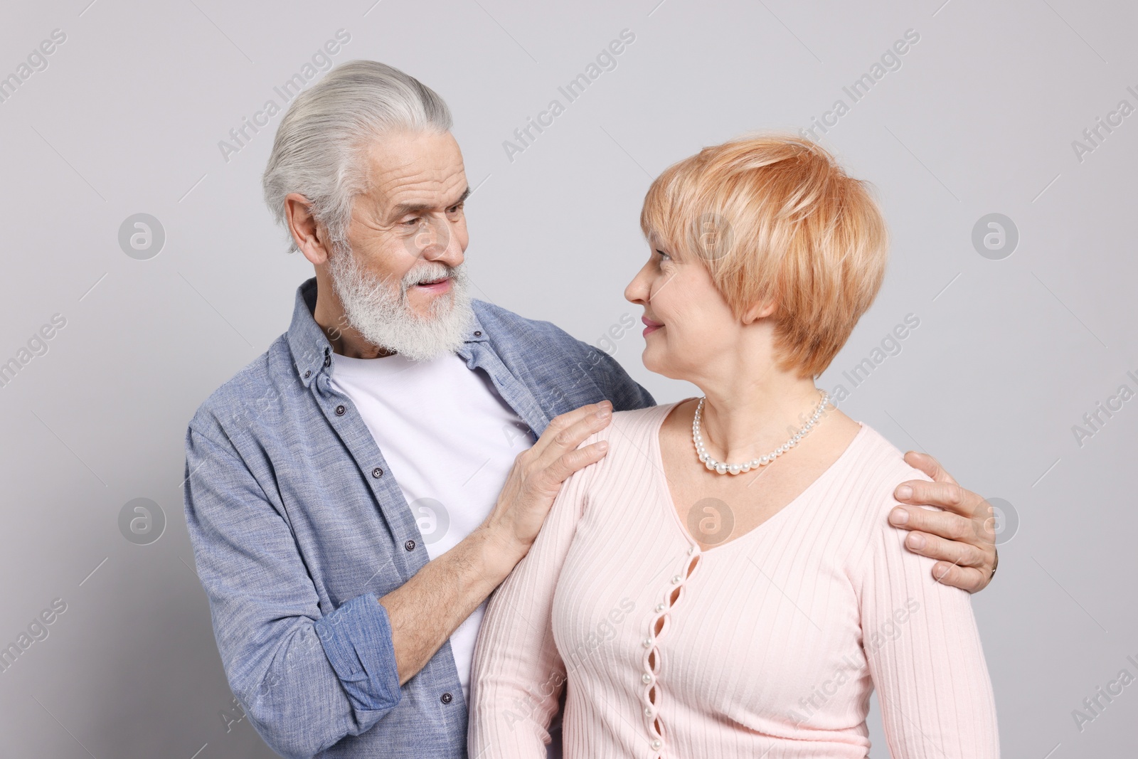 Photo of Lovely senior couple looking at each other on grey background