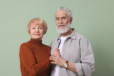 Photo of Portrait of lovely senior couple holding hands on green background