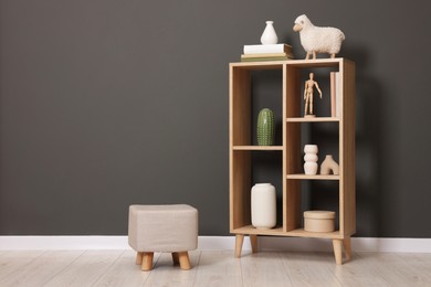 Photo of Shelving unit with different decor and pouf near grey wall indoors, space for text