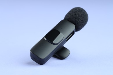 Photo of Lavalier microphone on light blue background, closeup