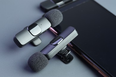 Photo of Lavalier microphones and smartphone on light grey background, closeup