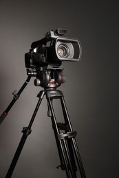 Photo of Modern video camera with tripod on grey background