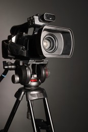 Photo of Modern video camera with tripod on grey background