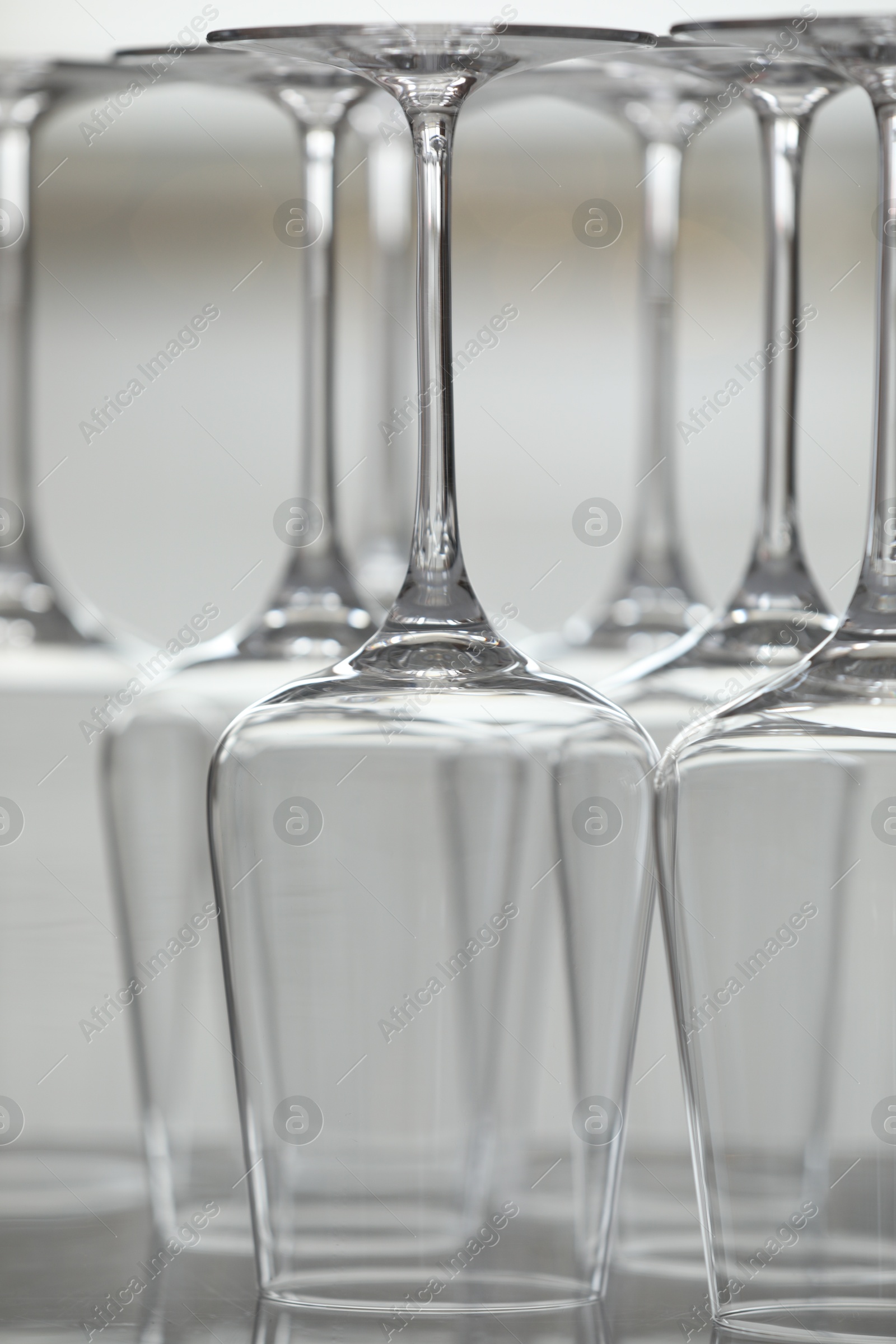 Upturned empty clean glasses on mirror surface against blurred background, closeup Photo of Upturned empty clean glasses on mirror surface against blurred background, closeup
