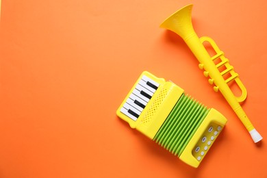 Photo of Toy accordion and horn on orange background, flat lay. Space for text