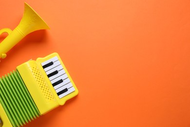 Photo of Toy accordion and horn on orange background, flat lay. Space for text