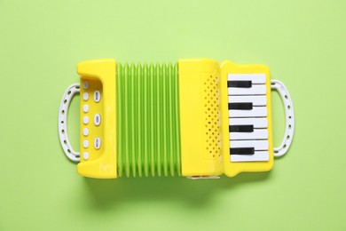 Photo of Toy accordion on green background, top view. Child's musical instrument