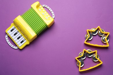 Photo of Bright toy accordion and tambourines on violet background, flat lay. Space for text