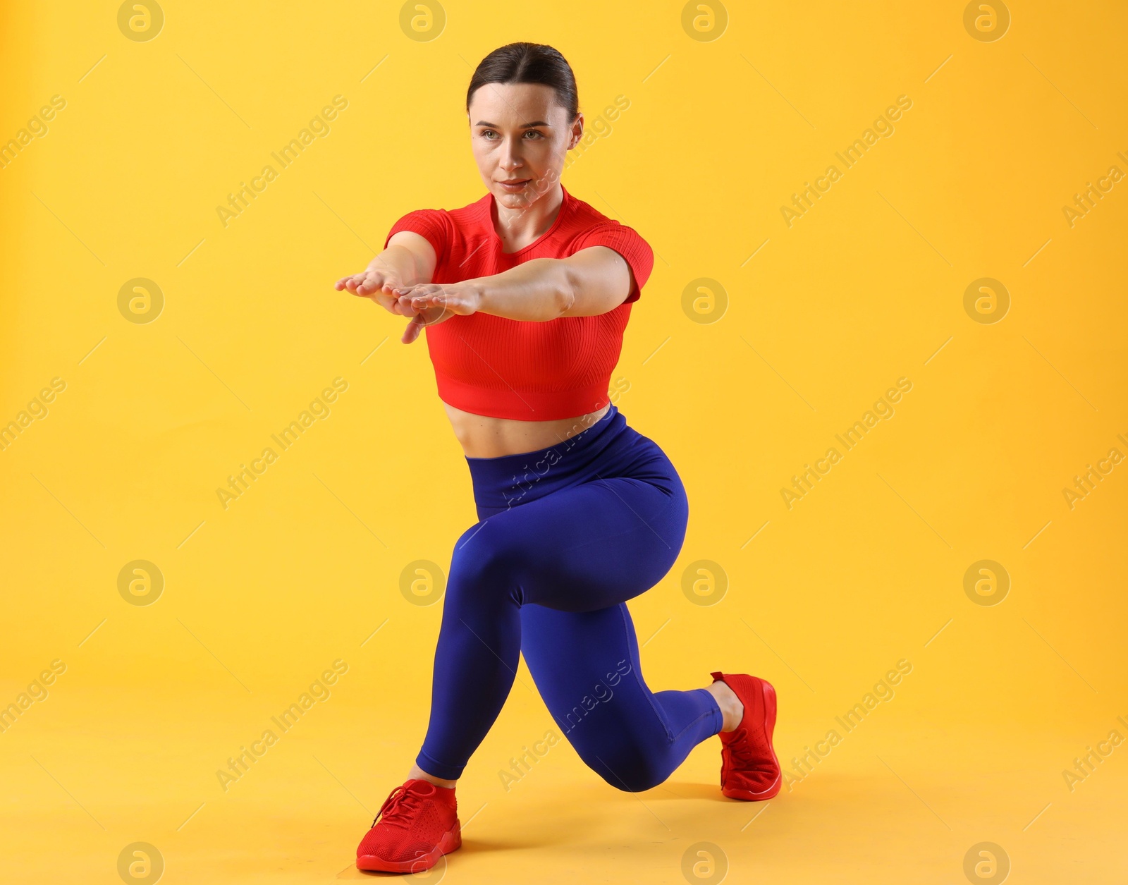 Photo of Woman in sportswear exercising on orange background