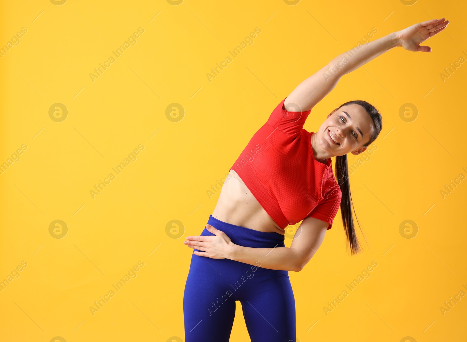 Photo of Woman in sportswear exercising on orange background, space for text