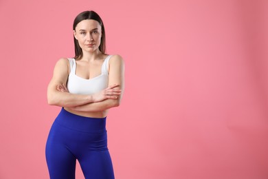 Woman in sportswear posing on pink background, space for text