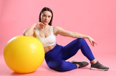 Photo of Woman in sportswear with fitness ball on pink background