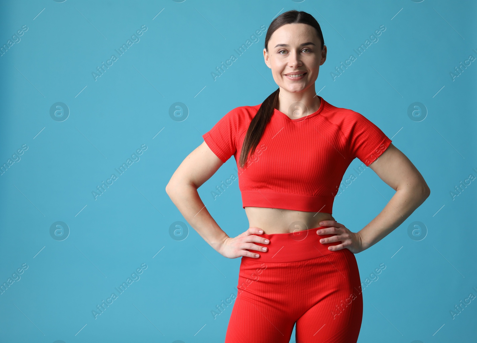 Photo of Woman in sportswear posing on light blue background, space for text