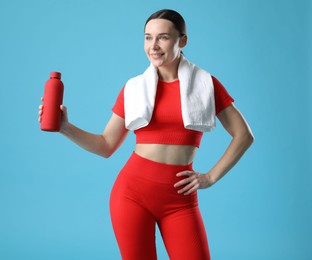 Photo of Woman in sportswear with water bottle and towel on light blue background