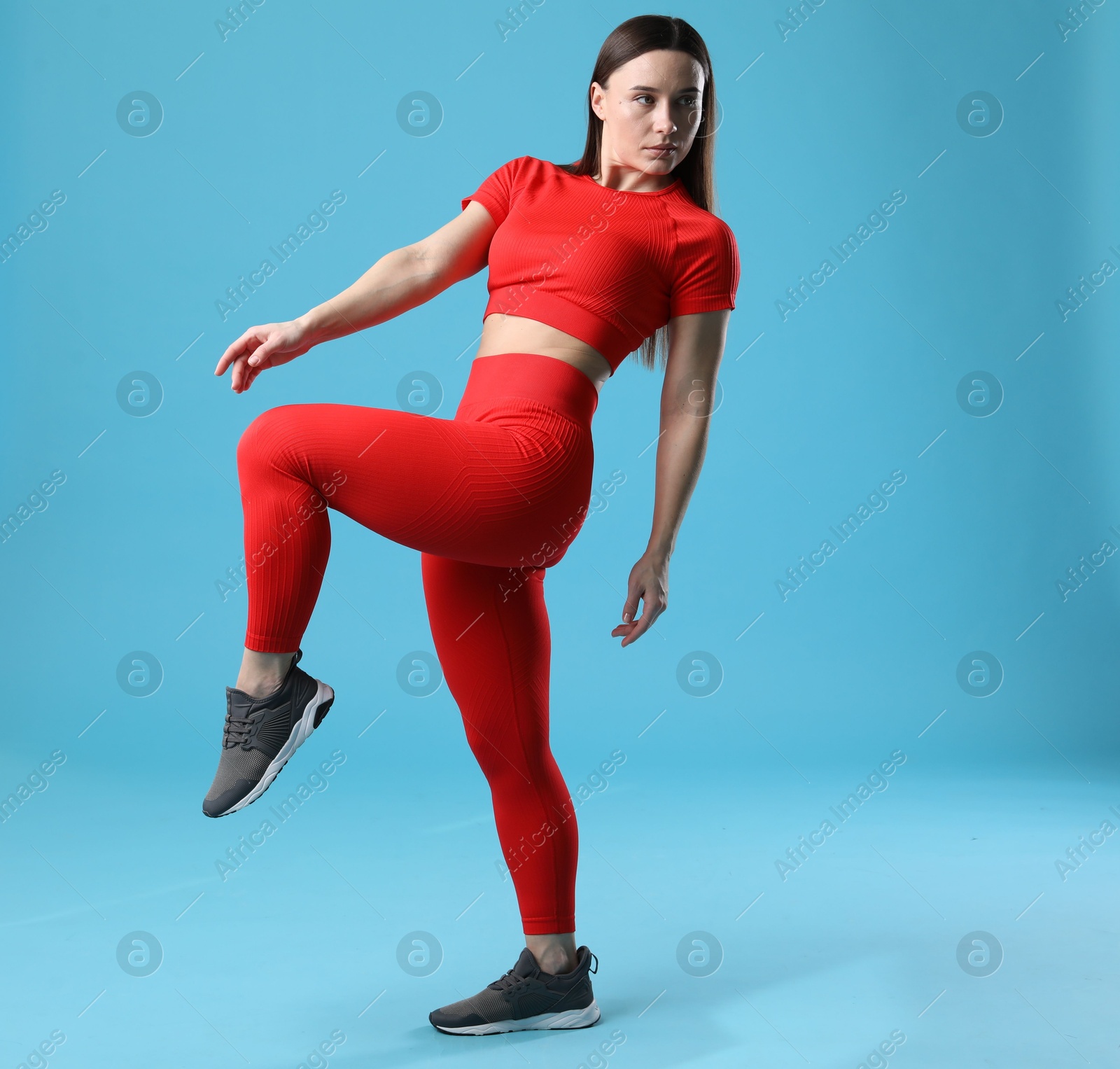 Photo of Woman in sportswear posing on light blue background