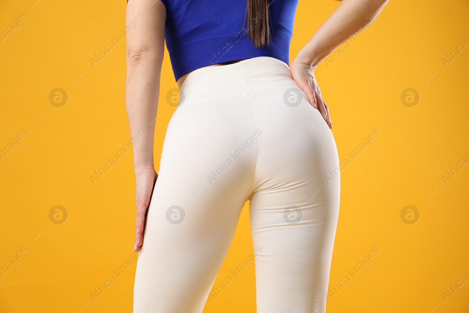 Photo of Woman in sportswear posing on orange background, closeup