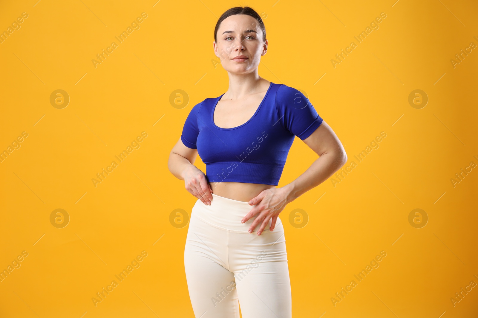 Photo of Woman in sportswear posing on orange background